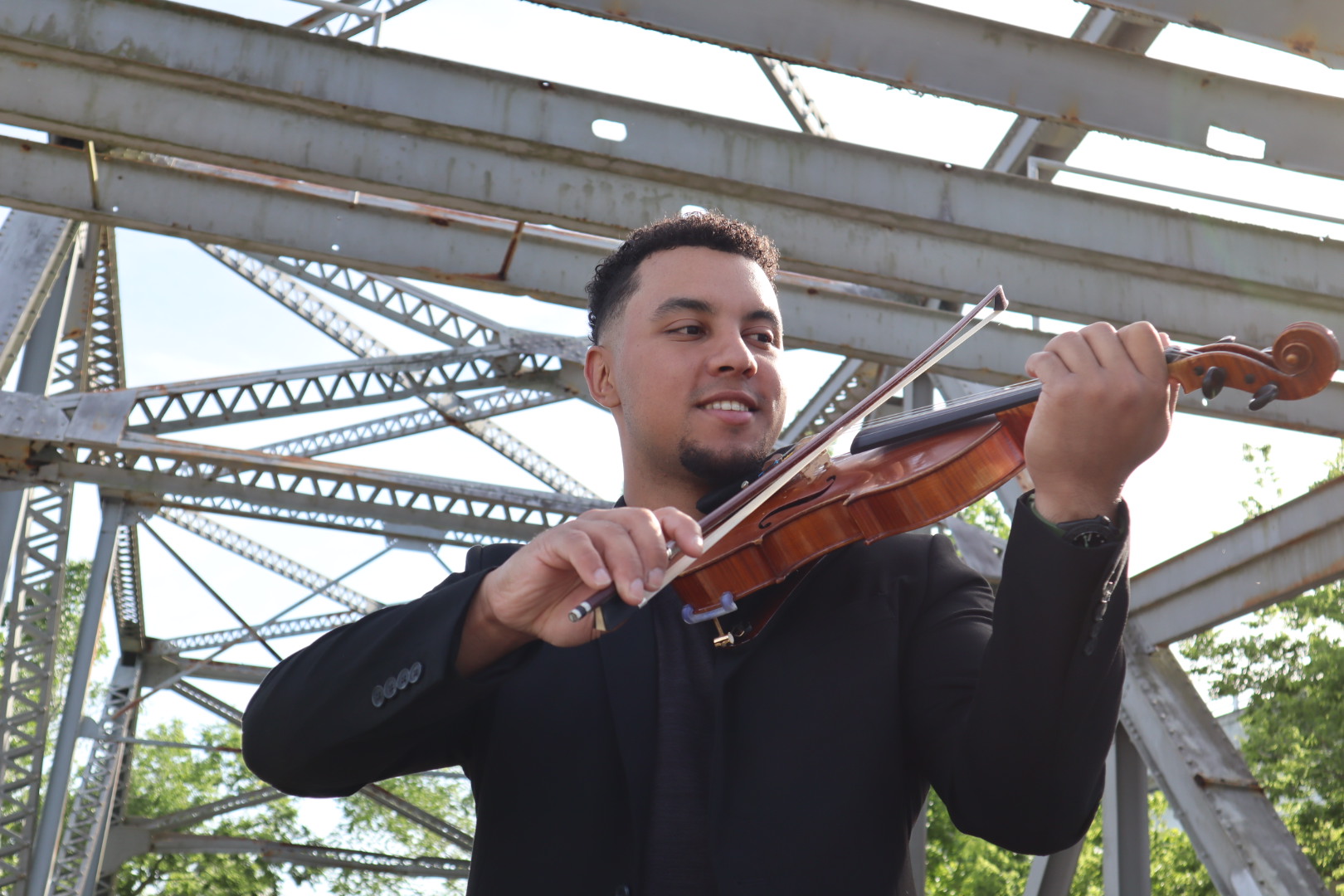Ian playing violin at metal structure