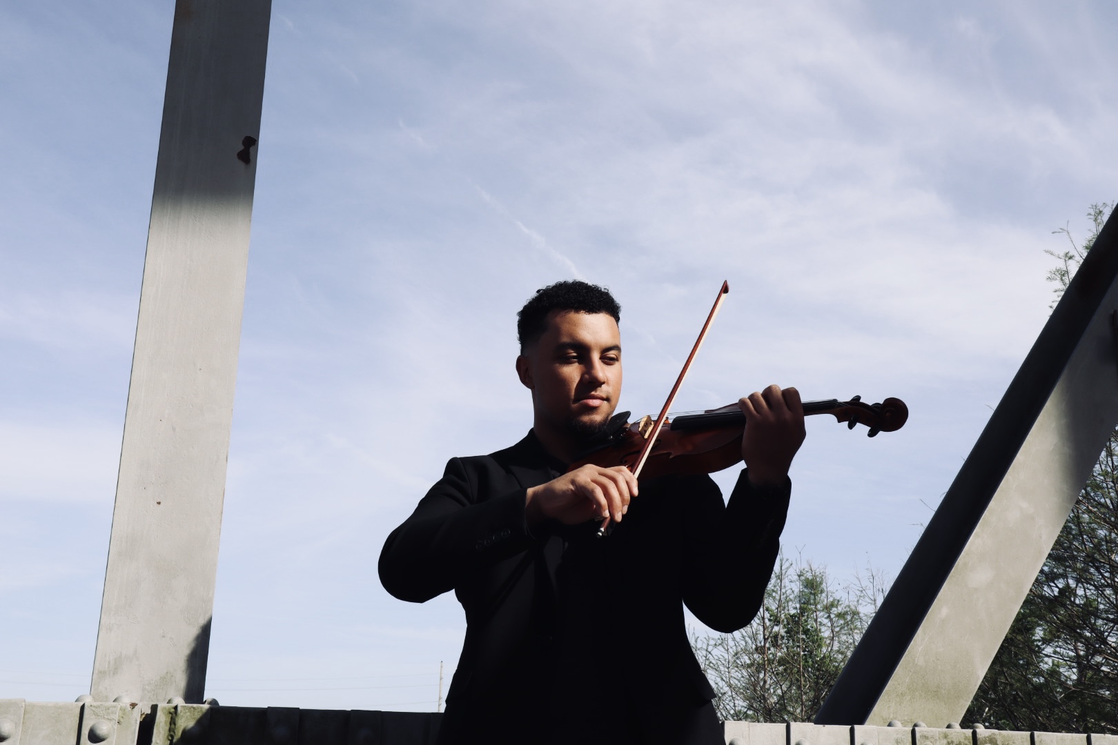 Ian playing violin under metal beams